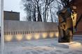 Abstrakcyjna, ciężka bryła pomnika na tle jasnej ściany z betonu architektonicznego 